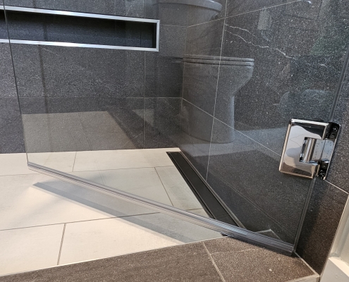 detail image of tile shower niche and glass shower door hinge