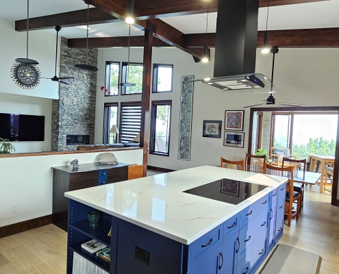 Blue kitchen island looking into living room with wood beams